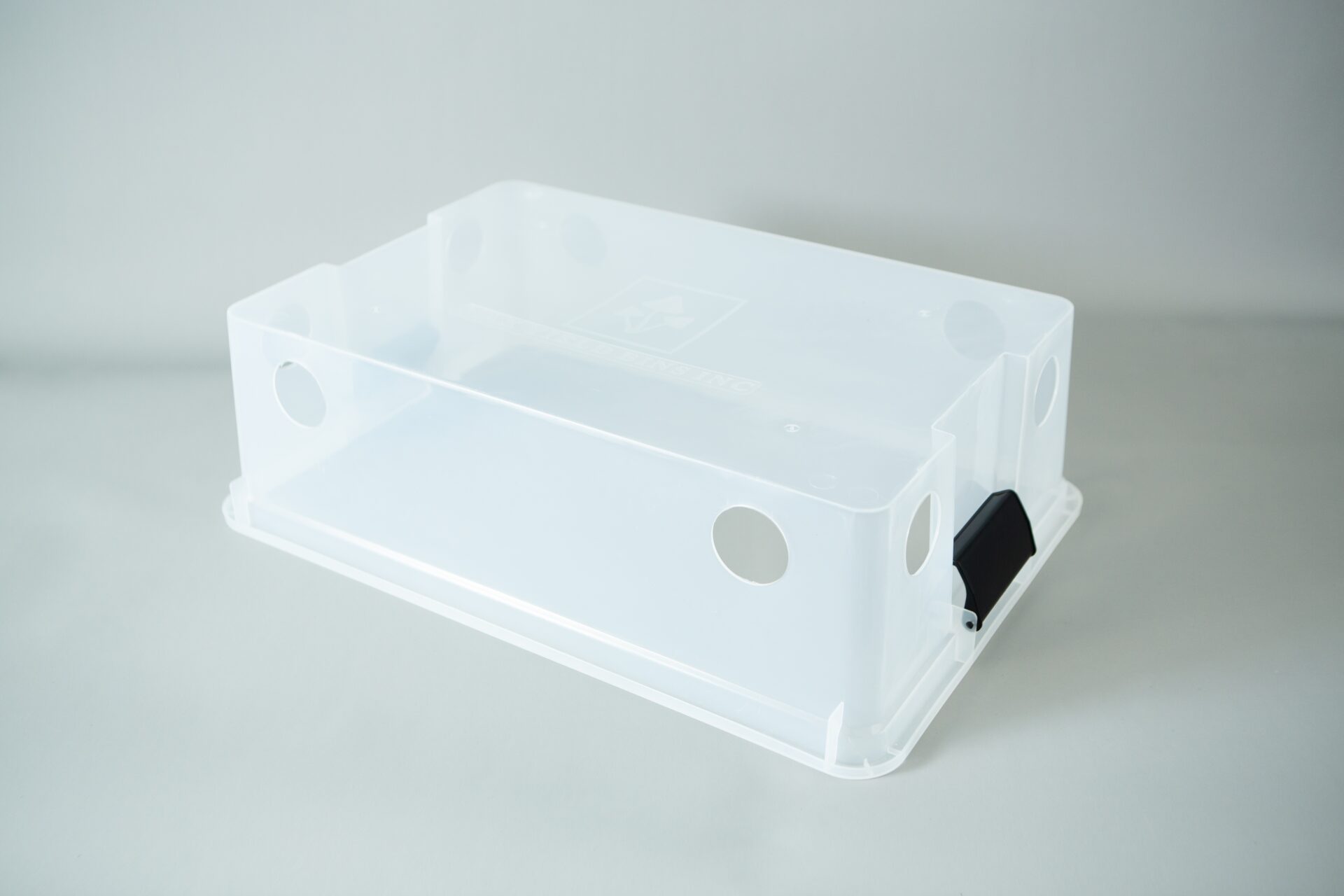 Monotub kit for Growing mushrooms- Max Yield Bins 2 A clear plastic monotub kit with circular holes and a black catch, designed for growing mushrooms, is placed on a light grey surface.