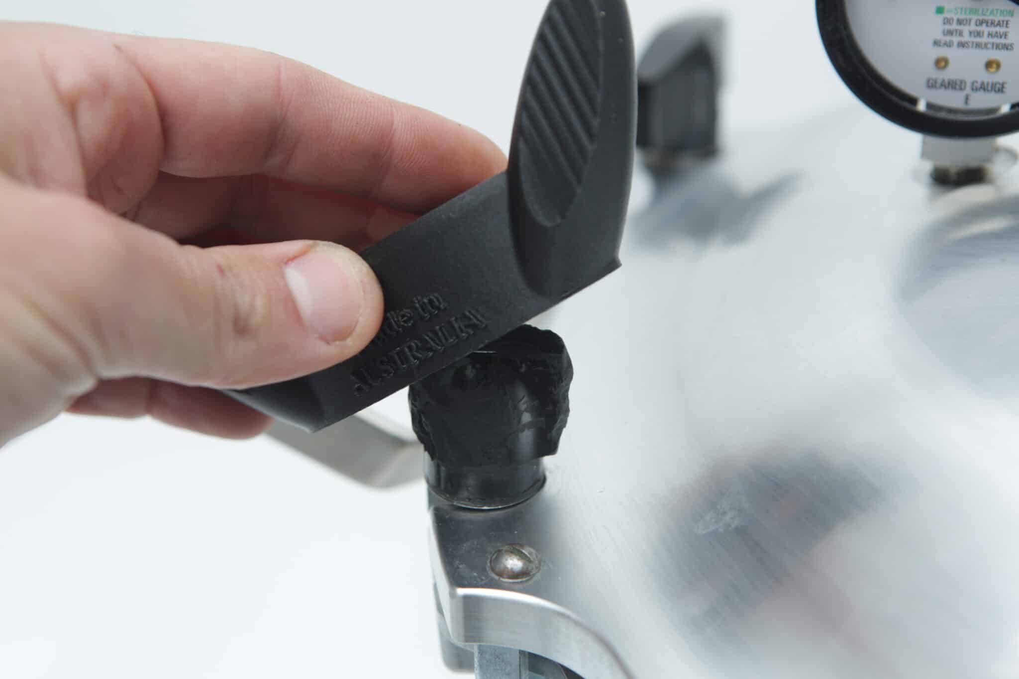 Wingnut Wrench for All American Steriliser | Rootlab Original | 3D Printed 4 A hand removes a black safety valve from the lid of an All American Tool stainless steel pressure cooker.