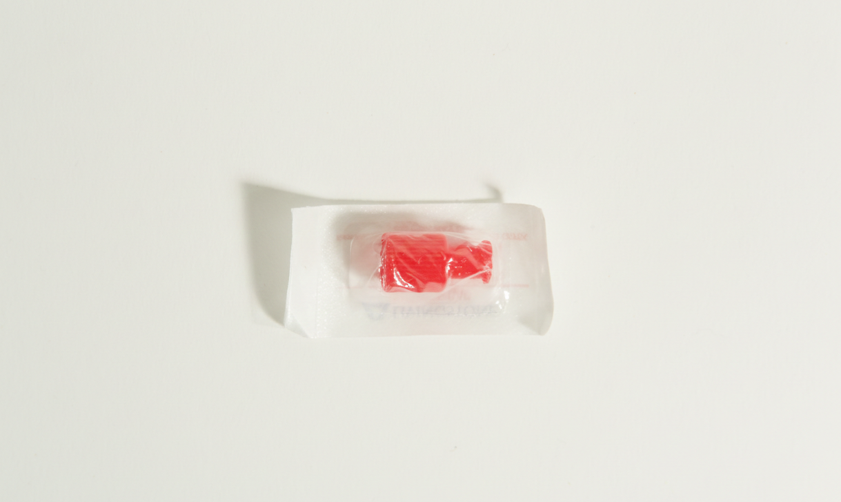 Sterile Syringe Cap for Standard Luer lock Syringe 2 A single red hard sweet in a clear plastic wrapper, resembling a sterile syringe cap, sits on a white background.