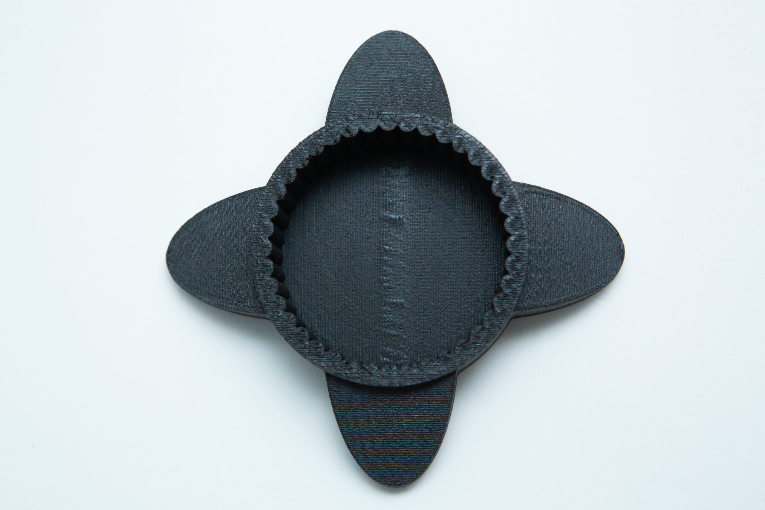 Reagent Bottle Cap Wrench | Rootlab Original | 3D Printed 2 A round, black, 3D-printed object with four oval flaps, placed on a white background.