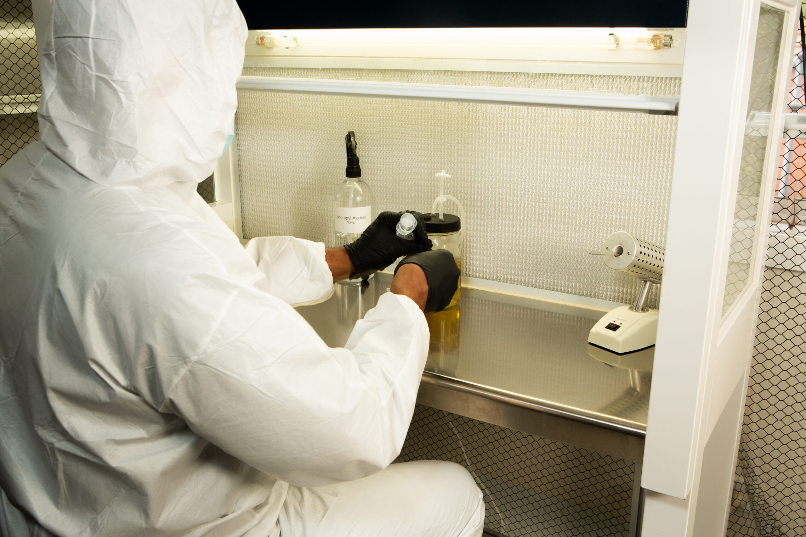 Horizontal Laminar Flowhood Cabinet | Clean bench 10 A person in protective gear works with lab equipment and liquids inside a sterile laboratory fume cupboard.