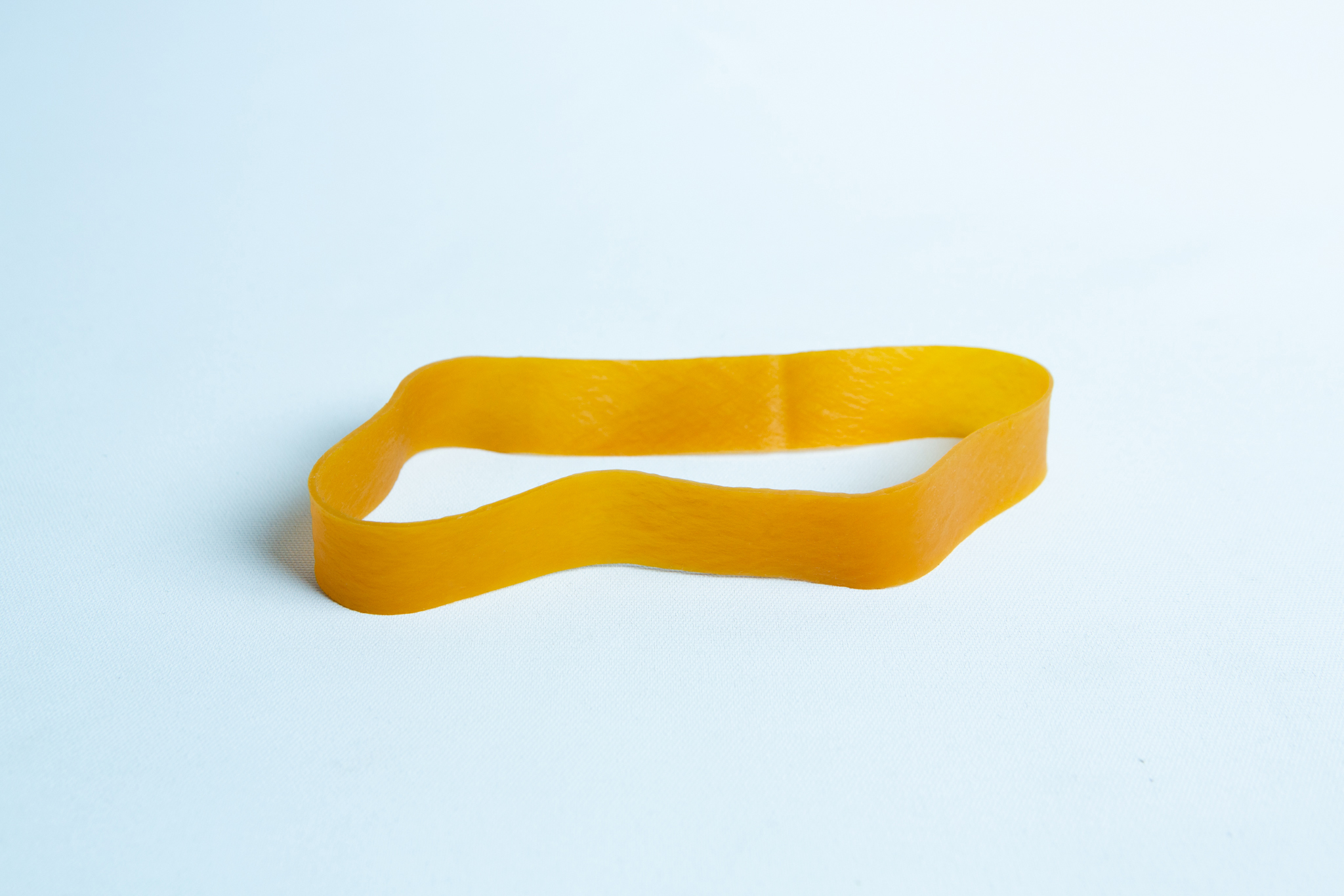 Fruiting Rubber Band for Mushroom growing 10pcs | Reusable 5 A single yellow elastic band lies flat on a light blue surface.