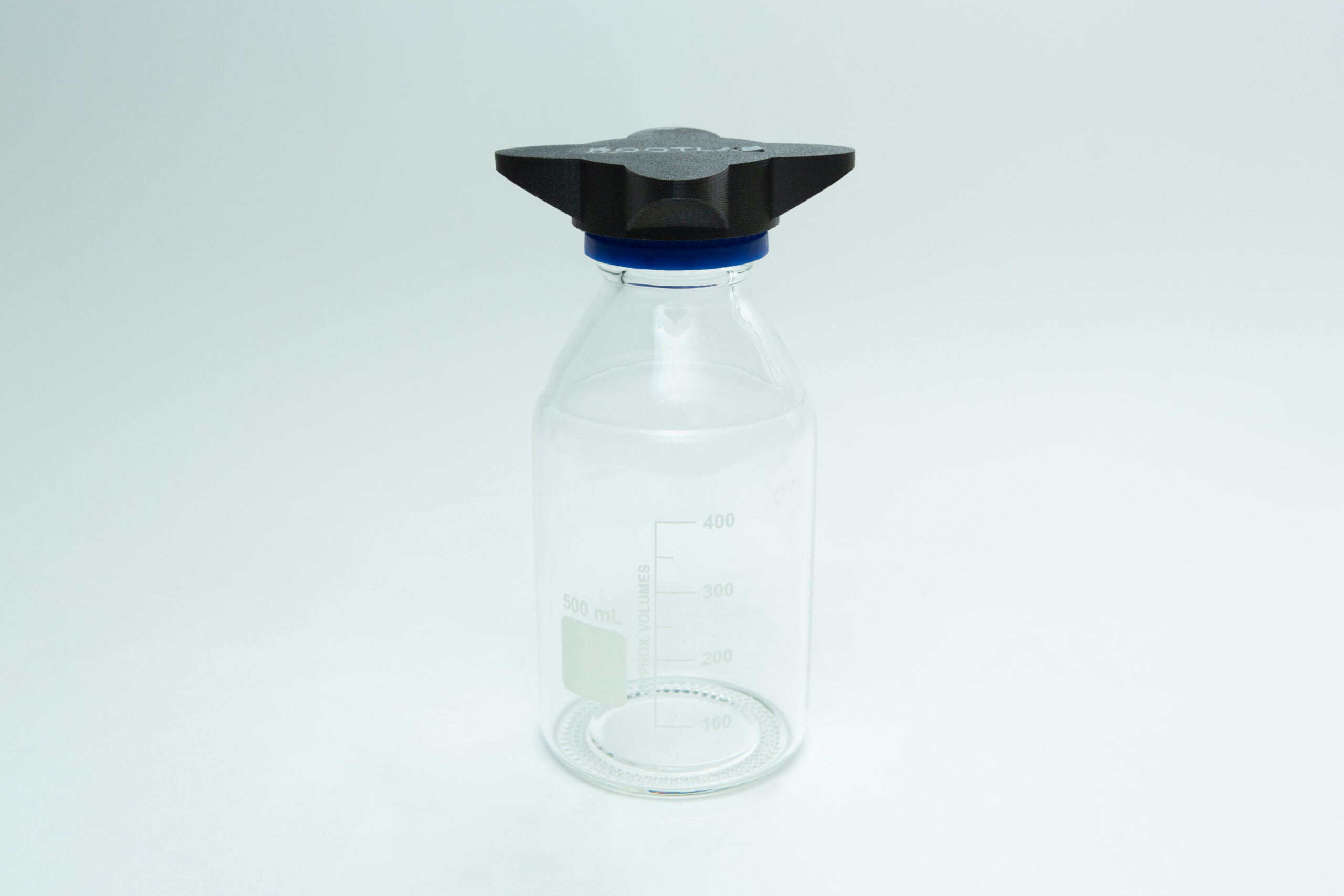 Reagent Bottle Cap Wrench | Rootlab Original | 3D Printed 7 Clear glass bottle with measurement markings and a black screw cap, placed on a plain white background.