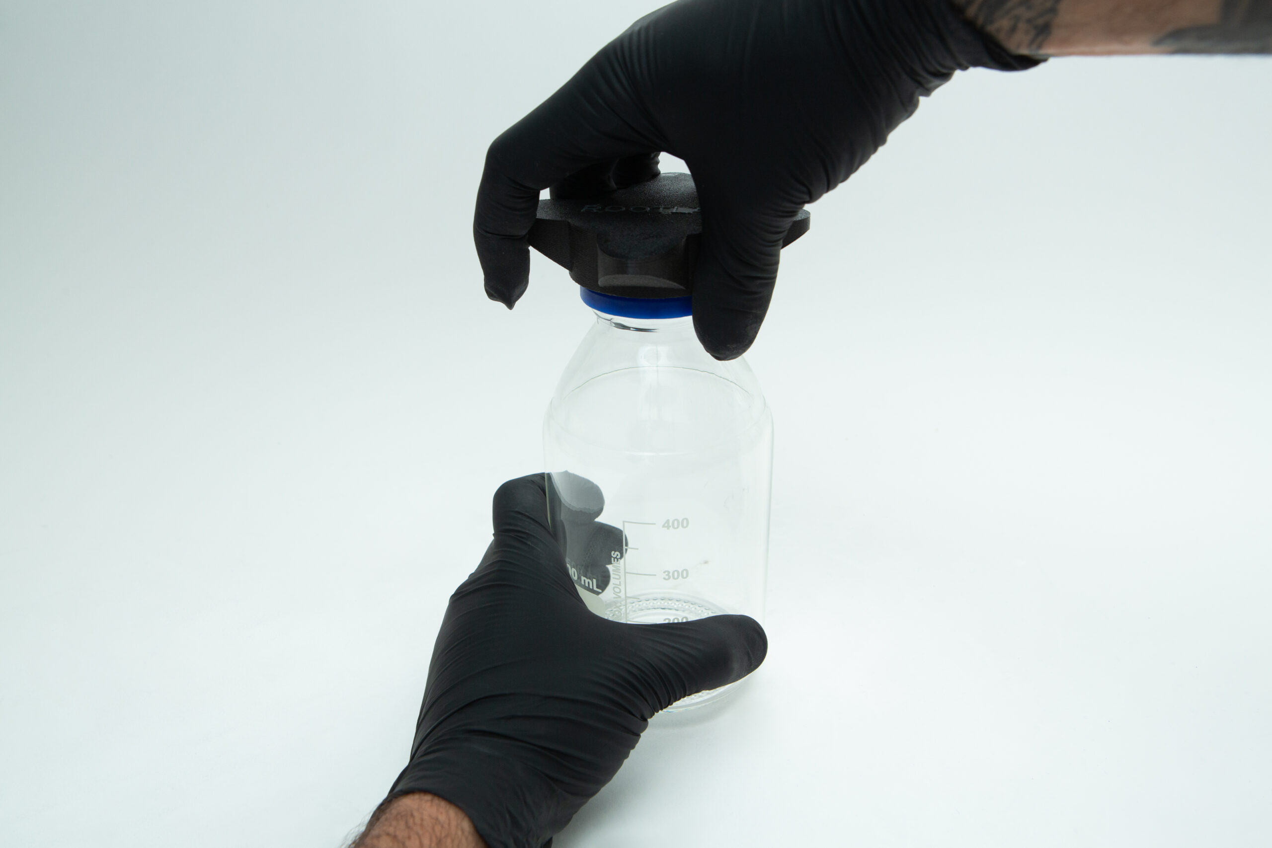 Reagent Bottle Cap Wrench | Rootlab Original | 3D Printed 5 Two gloved hands are sealing a clear glass jar with a black lid against a white background.