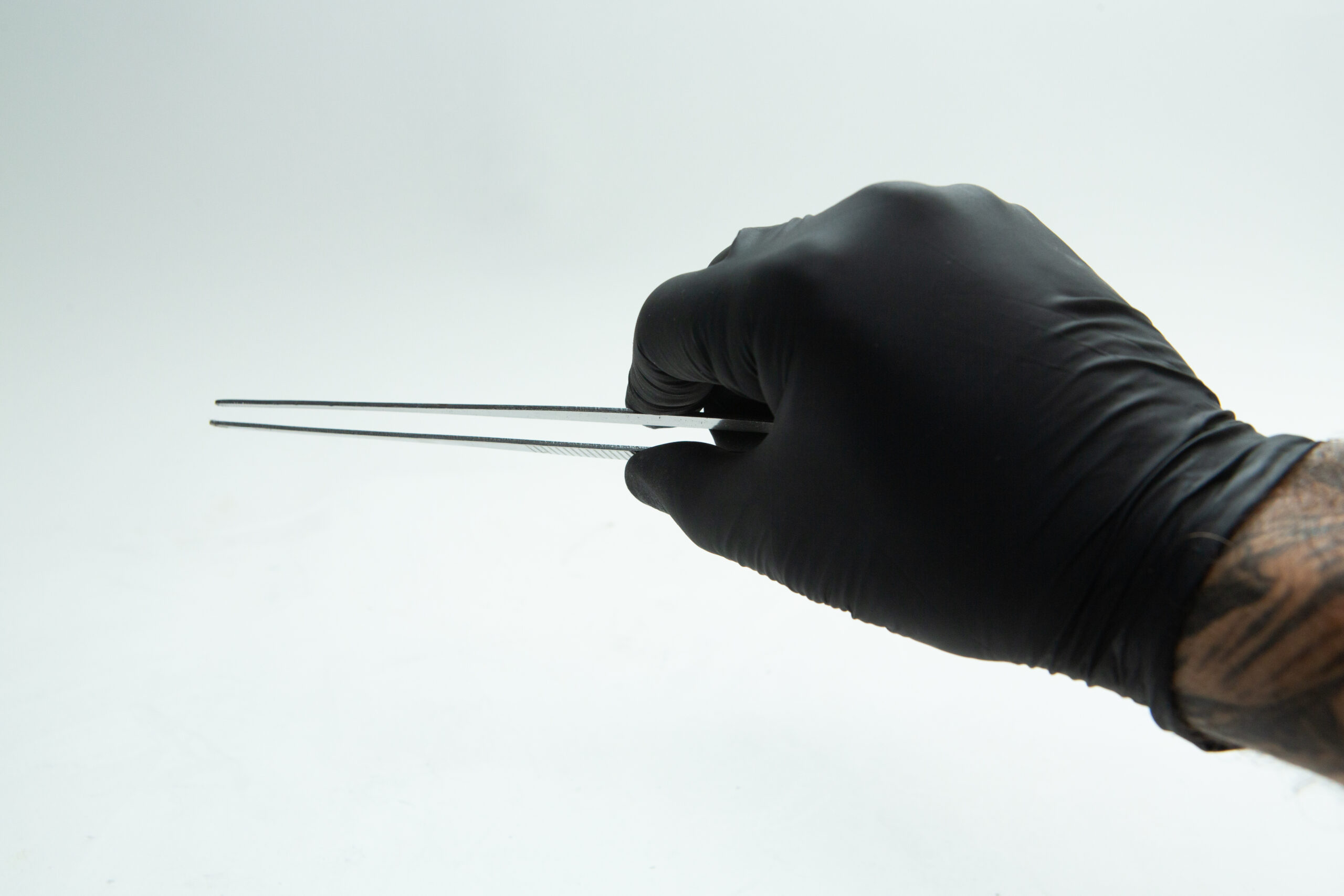 Stainless Steel Plant tissue culture Lab Forceps | Curved & Straight Tips | 25cm 8 A hand in a black glove holding metal tweezers against a white background.