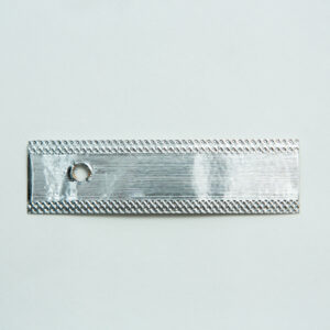A rectangular metallic strip with a small round hole near one end, placed on a plain white background.