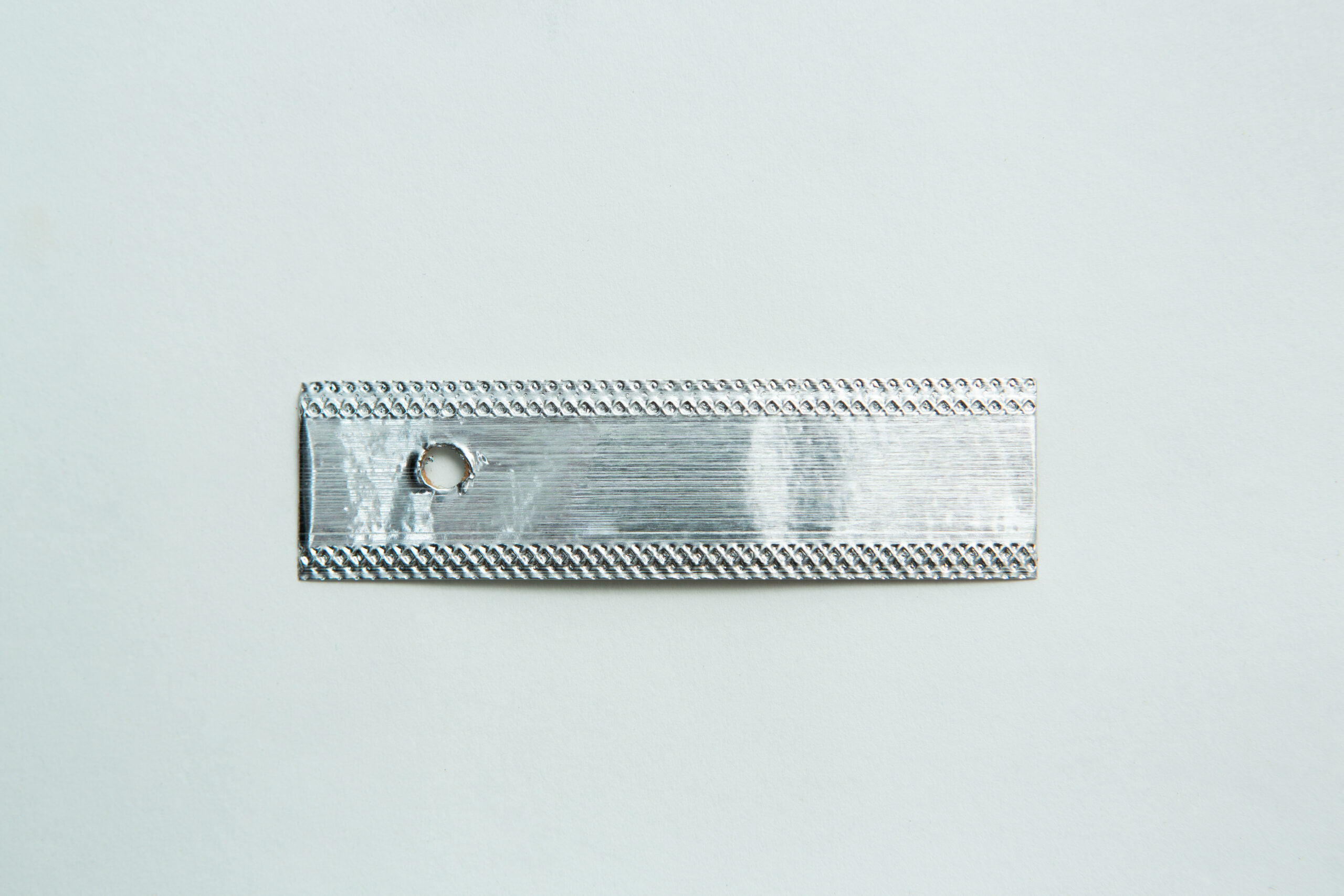 Aluminium Log Labelling Tags - Weather Safe 1 A rectangular metallic strip with a small round hole near one end, placed on a plain white background.