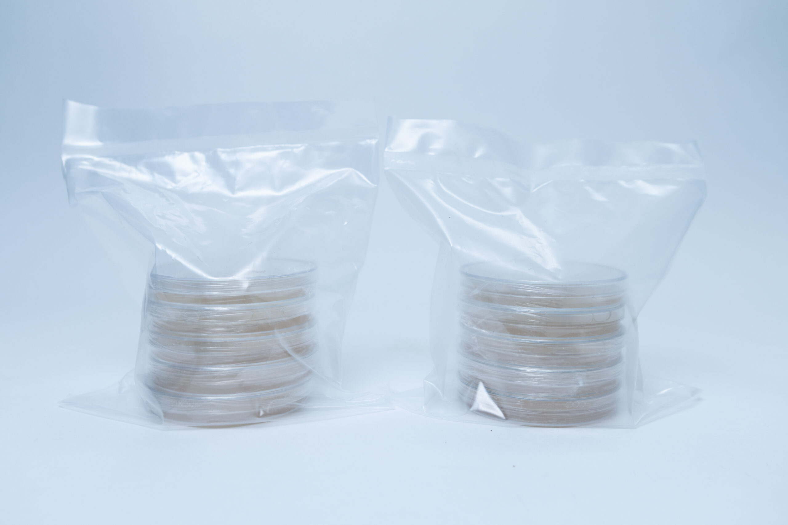 5 x Agar Plates (MEA) and 5 x Agar Plates (MEAG) Pre poured 90mm 2 Two stacks of petri dishes are sealed separately in clear plastic bags on a white background.