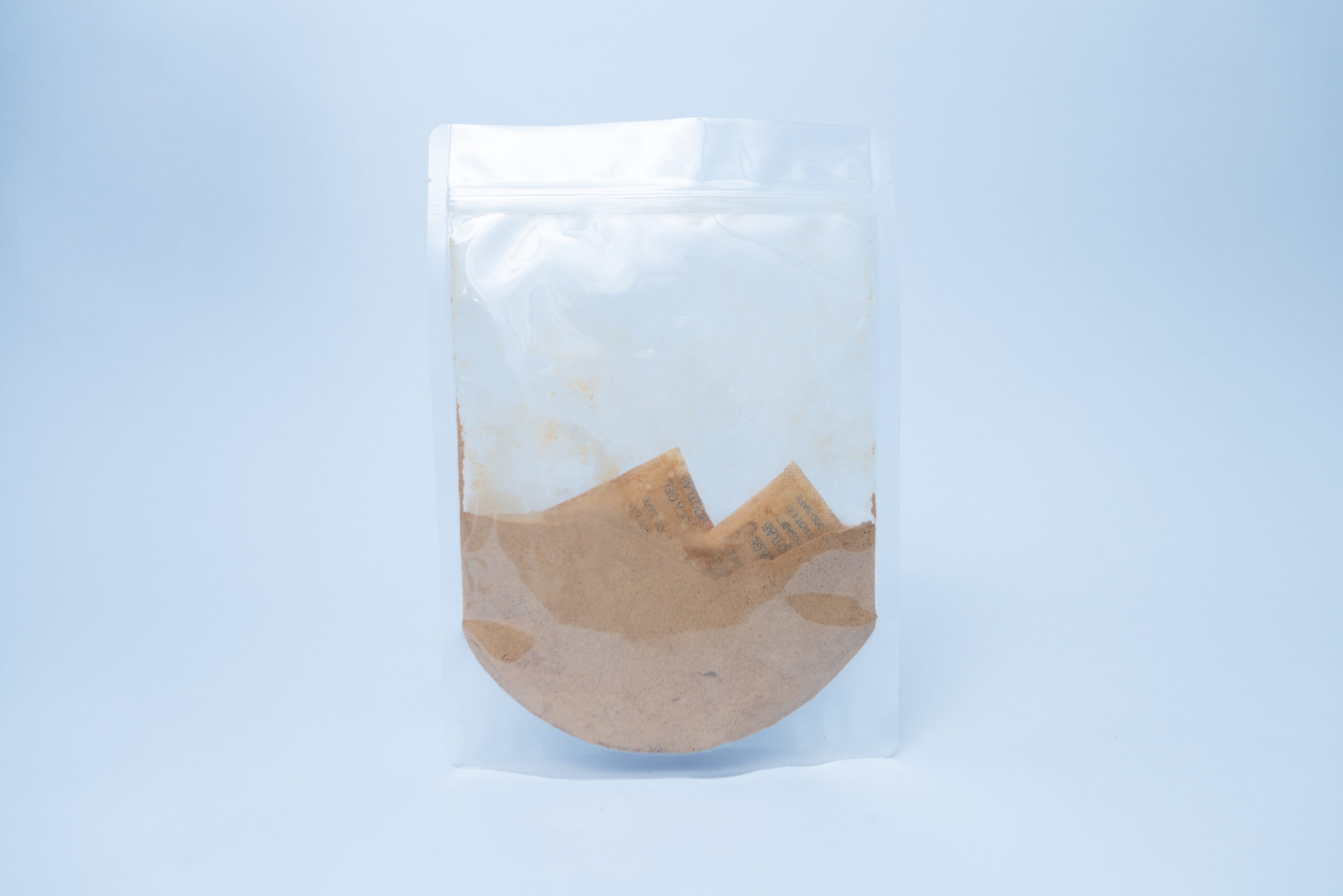 Australian Grown Dehydrated Cordyceps militaris (Powder) 3 Used brown coffee filter with grounds inside a clear resealable plastic bag, isolated on a light background.