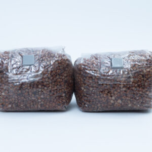 Home 7 Two sealed plastic bags filled with brown grains, placed side by side on a plain white background.