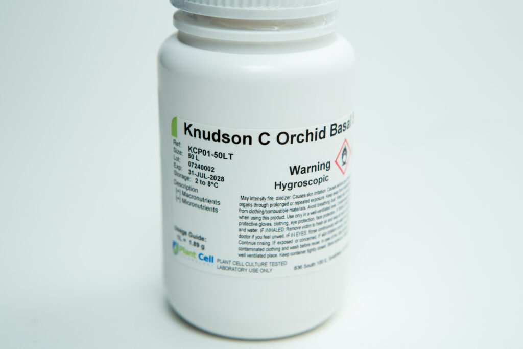 A white plastic bottle labelled Knudson C Orchid Base with warning text and storage instructions.